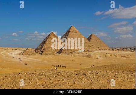 Complexe pyramidal de Gizeh depuis le point de vue panoramique avec des trains de chameaux et l'horizon du Caire : pyramides de Menkaure, Khafre et Khufu. Égypte, 17 février 2024 Banque D'Images
