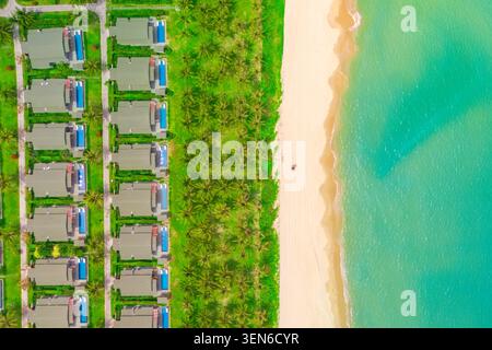 Vue aérienne de dessus de nombreux bâtiments en rangée de lignes identiques avec des jardins densément construits sur la plage de la côte de la mer océan. Maisons côte avec des cocotiers et s blancs Banque D'Images