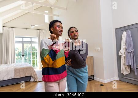 Femme indienne et femme afro-américaine discutant près de la grande fenêtre et fait lit dans la chambre Banque D'Images