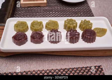 Bonbons coréens traditionnels Dasik sur une assiette blanche et thé vert versé dans une théière comme indiqué dans rkdwlsshrck 1.jpg et rkdwlsshrck.jpg détails sains. Banque D'Images