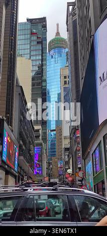 HONG KONG - 18 JUILLET 2023 : une perspective verticale à angle bas regardant à travers un canyon urbain dense vers une façade de bâtiment en verre bleu emblématique. Banque D'Images