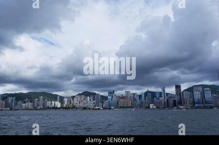 HONG KONG - 18 JUILLET 2023 : un large panorama de nuages sombres et dramatiques de la mousson roulant sur les gratte-ciel de l'île de Hong Kong. Banque D'Images