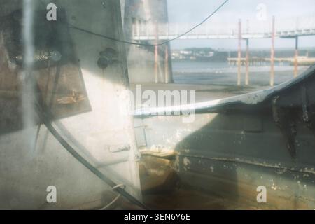 Regardant à travers une petite fenêtre de bateau dans Pembroke Dock. Clairement visible sont les bateaux abandonnés en détresse et la coque altérée. Banque D'Images