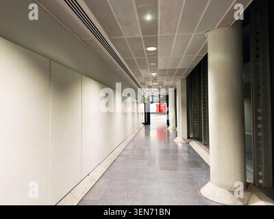 Manchester, Royaume-Uni - 20 mai 2026 : couloir d'aéroport vide minimal à Manchester avec piliers, sols polis, éclairage par le ciel et panneaux directionnels Banque D'Images