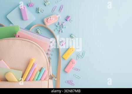 Ouverture de sac à dos révélant une collection de fournitures scolaires et articles de papeterie, y compris des cahiers, surligneurs, gommes et classeurs, dispersé sur Banque D'Images