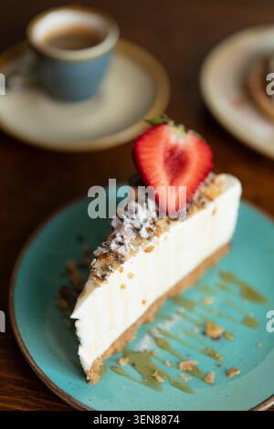 Dégustez une riche tranche de cheesecake garnie de fraises fraîches et d'un accompagnement d'espresso Banque D'Images