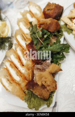 Tranches de pain frais, morceaux frits croustillants et légumes verts sur assiette blanche. Les articles frits sont dorés, salés et richement texturés. Les herbes et la laitue ajoutent un cris Banque D'Images