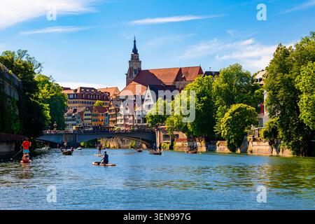 Journée d'été ensoleillée sur la rivière Neckar à Tübingen, avec des punts et des planches à paddleboards qui glissent devant des façades colorées à colombages, un pont de pierre et le GOT Banque D'Images