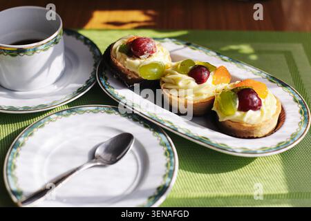 Sandwichs ouverts avec fruits et café servis sur table. Petit déjeuner maison et concept de repas du matin en gros plan. Banque D'Images