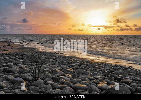 Côte rocheuse de la mer Baltique au coucher du soleil doré avec des vagues et des rochers en Lettonie Banque D'Images