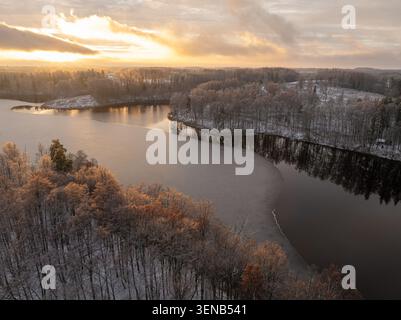 Lac Dubulka partiellement gelé au lever du soleil dans la paroisse d'Aglona, Latgale, Lettonie, vue aérienne par drone du paysage hivernal Banque D'Images