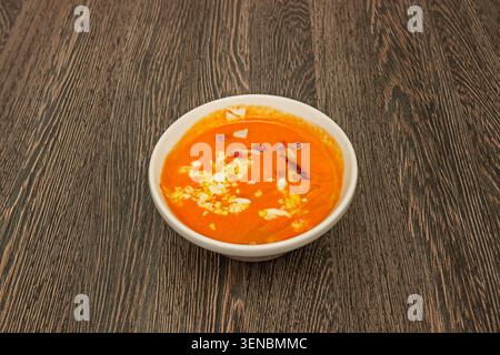 Un gros plan du dessus montre une assiette profonde de salmorejo réfrigéré, mettant en évidence les cubes irrégulièrement distribués de jambon ibérique, des rubans de e dur Banque D'Images