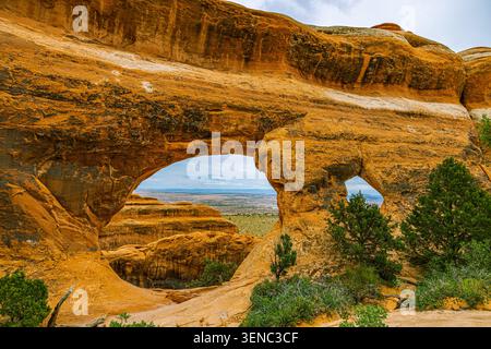 Les structures à double ouverture distinctives de partition Arch se situent sur un fond de canyon accidenté dans le parc national d'Arches. Banque D'Images