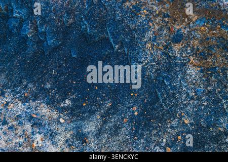 Gros plan détaillé et de haut en bas d'un sol sombre et carboné mélangé à du sable fin ressemblant à du charbon de bois et à des morceaux de couches de pierre bleu-gris. Banque D'Images