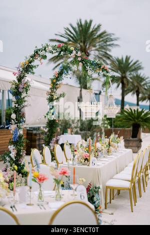 Réception de mariage en plein air élégante avec arc floral et lustres Banque D'Images