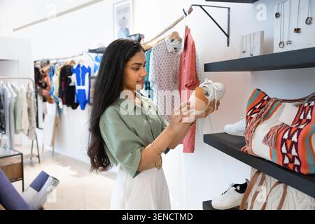Femme examinant sneaker dans un magasin de vêtements élégant Banque D'Images