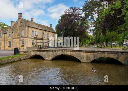 Vue du pont sur la rivière Windrush , Bourton-on-the-Water, les Cotswolds, Gloucestershire, Angleterre, Royaume-Uni montrant le pub Kingsbridge Inn sur la rivière Banque D'Images