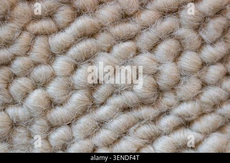 Vue macro de fibres de laine tricotées épaisses, fond de texture textile neutre chaud pour le design d'intérieur et les concepts de mode Banque D'Images