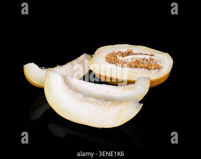 Cucumis melo de melon mûr tranché avec des graines visibles et des quartiers juteux, fruits sucrés biologiques frais avec reflet sur une surface noire brillante, stuc premium Banque D'Images