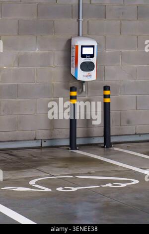 Station de charge de véhicule électrique Galp sur un mur de briques dans un parking intérieur avec symbole de voiture peint sur le sol Banque D'Images