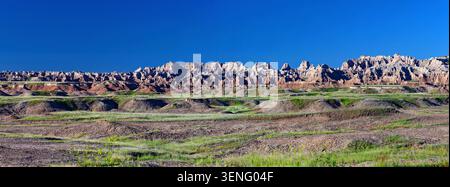 Une large vue panoramique sur les formations géologiques spectaculaires et le paysage érodé du parc national des Badlands sous un ciel bleu clair Banque D'Images