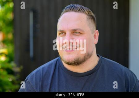 Portrait d'un jeune homme positif souriant naturellement tout en regardant de côté. Image de style de vie authentique représentant l'optimisme, la convivialité, la confiance, Banque D'Images
