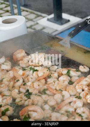 Gros plan de la cuisson des crevettes sur une plaque chauffante avec des herbes dans une cuisine ou un cadre de restauration en France. Banque D'Images