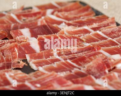 Gros plan de jambon séché tranché disposé sur une planche, typique de la charcuterie européenne, en France. Banque D'Images