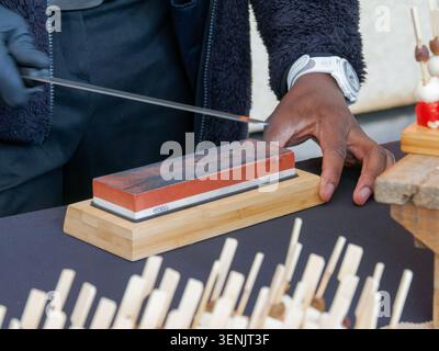 Gros plan d'un professionnel tranchant du jambon séché à partir d'une jambe de jambon à l'aide d'un couteau, typique de la charcuterie européenne, en France. Banque D'Images