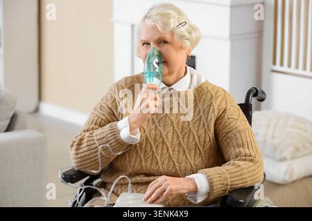 Femme âgée en fauteuil roulant utilisant le nébuliseur à la maison Banque D'Images