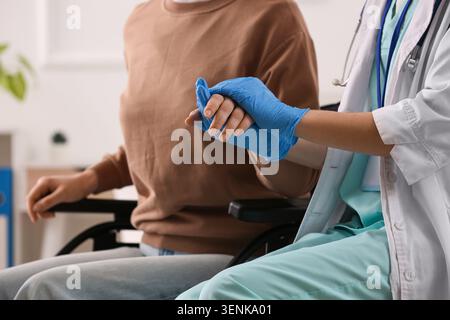 Professionnel de la santé portant des gants bleus tenant les patients par la main, fournissant un soutien et des soins compatissants dans le milieu de la santé Banque D'Images
