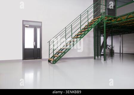 Intérieur moderne de loft industriel avec escalier en métal vert et murs blancs, design d'espace de bureau vide Banque D'Images
