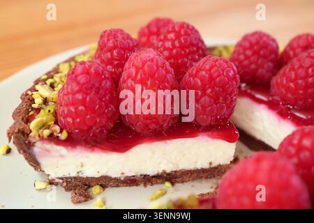 Plan macro d'une tranche de tarte aux framboises montrant une couche de fromage à la crème et une croûte de chocolat Banque D'Images
