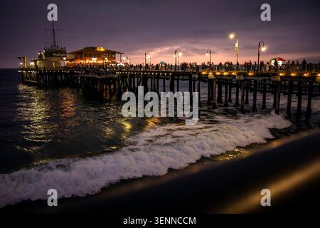 Santa Monica Pier illuminé au crépuscule avec des foules et des lumières se reflétant sur l'océan Pacifique, Los Angeles, Californie, États-Unis. Banque D'Images