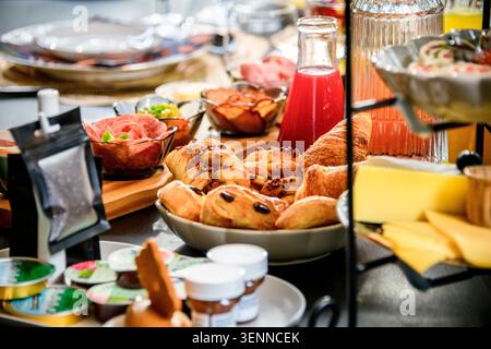 Copieux petit déjeuner buffet avec croissants, viennoiseries, charcuterie, jus de fruits et fromage. Brunch abondant de l'hôtel aux tons chaleureux et accueillants. Banque D'Images