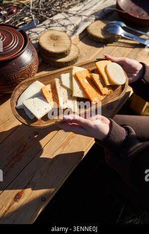 Dégustation de fromages sur une planche de bois sous le ciel ouvert. Banque D'Images