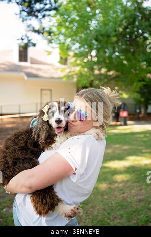 Femme câlin et embrassant un épagneul senior dans une cour ensoleillée Banque D'Images