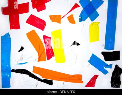 Assortiment de morceaux de ruban adhésif déchiré de plusieurs couleurs et formes dispersés sur une surface blanche, soulignant leurs textures et leur attrait visuel Banque D'Images