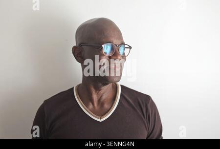 Homme noir chauve mature dans des lunettes regardant loin et souriant Banque D'Images