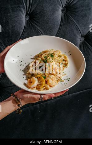Femme tenant un bol frais de pâtes aux crevettes au citron Banque D'Images