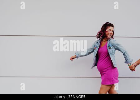 Femme enceinte joyeuse se tenant les mains et marchant Banque D'Images