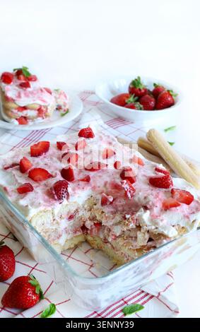 Tiramisu à la fraise. Dessert italien traditionnel à base de fraises fraîches et de crème de mascarpone, servi dans un plat en verre sur une nappe à carreaux. Banque D'Images