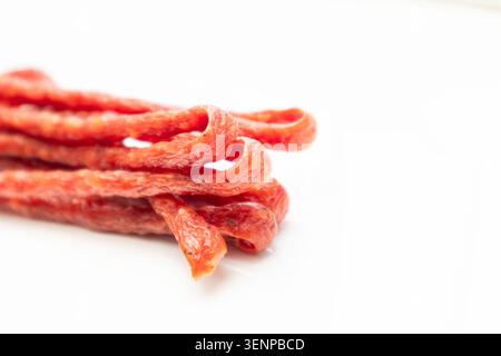 Saucisse de porc ou de boeuf, saucisses sèches, bâtonnet de viande fumé. Polissez un gros plan de saucisse mince, long et sec sur un fond blanc Banque D'Images