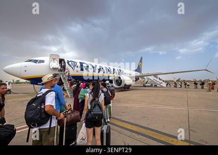 Passagers embarquant sur un vol Ryanair à l'aéroport Marrakech-Menara, Maroc. Maroc, Marrakech - 12 août 2023 : un groupe de passagers attendant de monter à bord d'un avion Ryanair sur le tarmac de l'aéroport RAK de Marrakech-Menara. Les voyageurs sont vus avec leurs bagages près des escaliers de l'avion sous un ciel nuageux. Marrakech Maroc Copyright : xGennaroxLeonardix Banque D'Images
