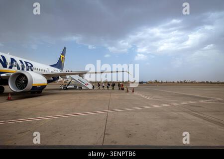 Passagers embarquant dans un avion Ryanair à l'aéroport de Marrakech-Menara, Maroc. Maroc, Marrakech - 12 août 2023 : un plan large d'un avion Ryanair stationné sur le tarmac de l'aéroport RAK de Marrakech-Menara, avec un petit groupe de passagers marchant vers les escaliers d'embarquement sous un ciel nuageux spectaculaire. Marrakech Maroc Copyright : xGennaroxLeonardix Banque D'Images