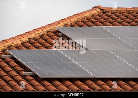 Vue rapprochée des panneaux solaires photovoltaïques modernes installés sur un toit traditionnel en terre cuite. Banque D'Images