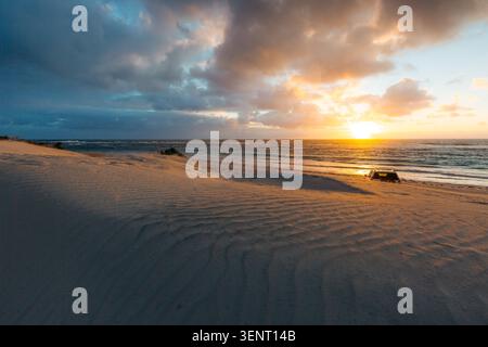 Véhicule tout-terrain voyage le long d'une plage australienne isolée au coucher du soleil pour une aventure Banque D'Images