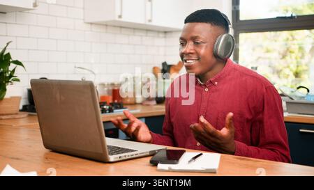 Réunion d'affaires à distance avec l'homme souriant portant des écouteurs au bureau de cuisine à la maison pour la consultation financière Banque D'Images