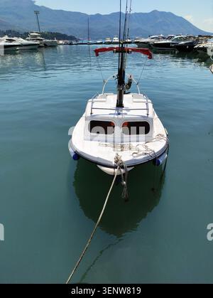 Un petit bateau à moteur blanc vieux est attaché au quai avec une corde. Un bateau de pêche typique est amarré dans un port maritime. Transport par eau. Loisirs actifs Banque D'Images