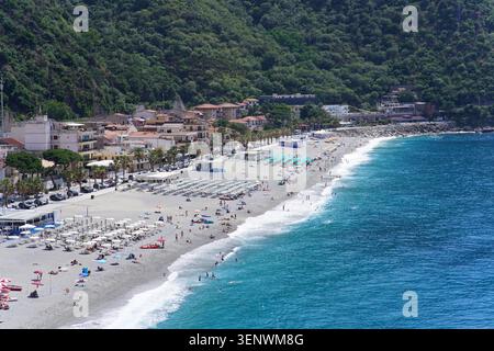 Vue aérienne de Scilla Beach bondée avec des parasols, ville et colline verte à Scilla, Calabre, Italie par jour ensoleillé. Banque D'Images